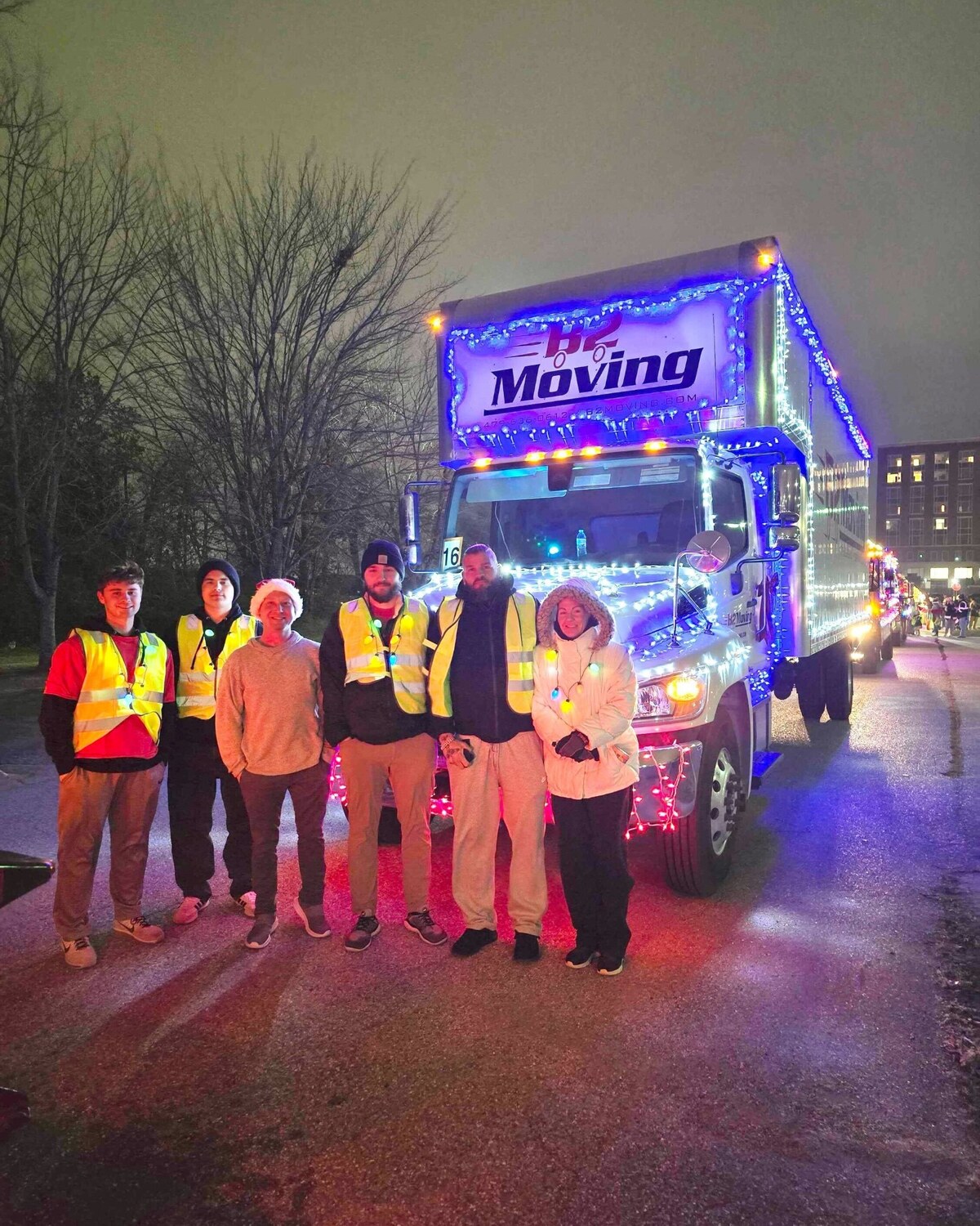 B2 Moving teammates beside a decorated truck at the 2025 Bentonville Christmas Parade