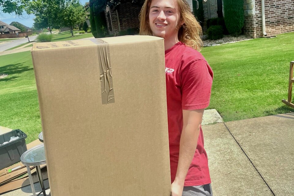 Jacob McKinney carrying a large boxed household item during a B2 Moving job