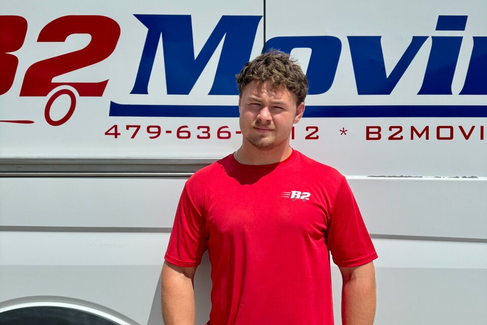Kaden McCrary, a B2 Moving mover, standing in front of a B2 service van