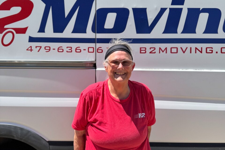 Shirley Baker, a B2 Moving professional packer, standing beside the B2 packing service van