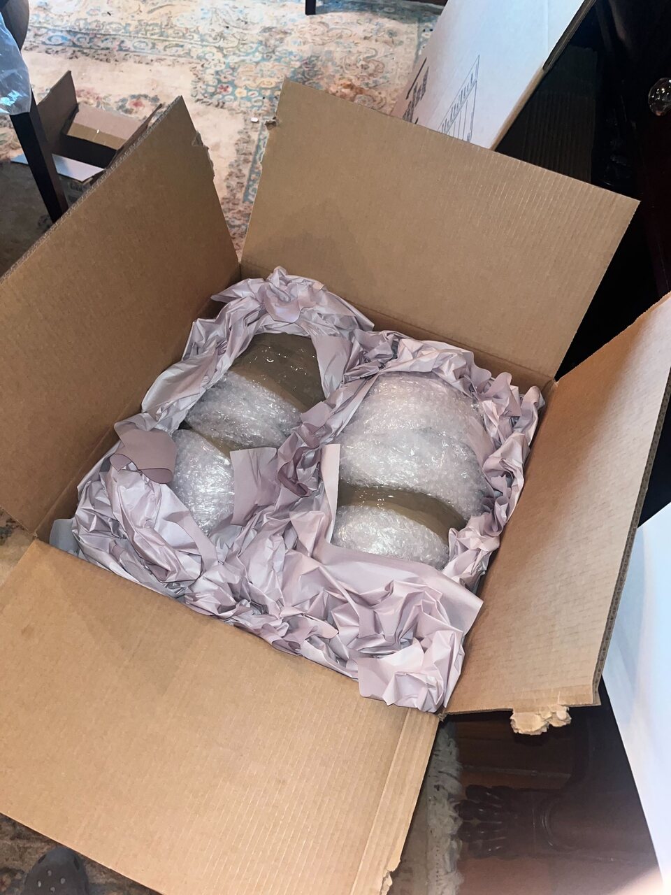 Fragile household items protected with bubble wrap, clean paper, and a sturdy carton