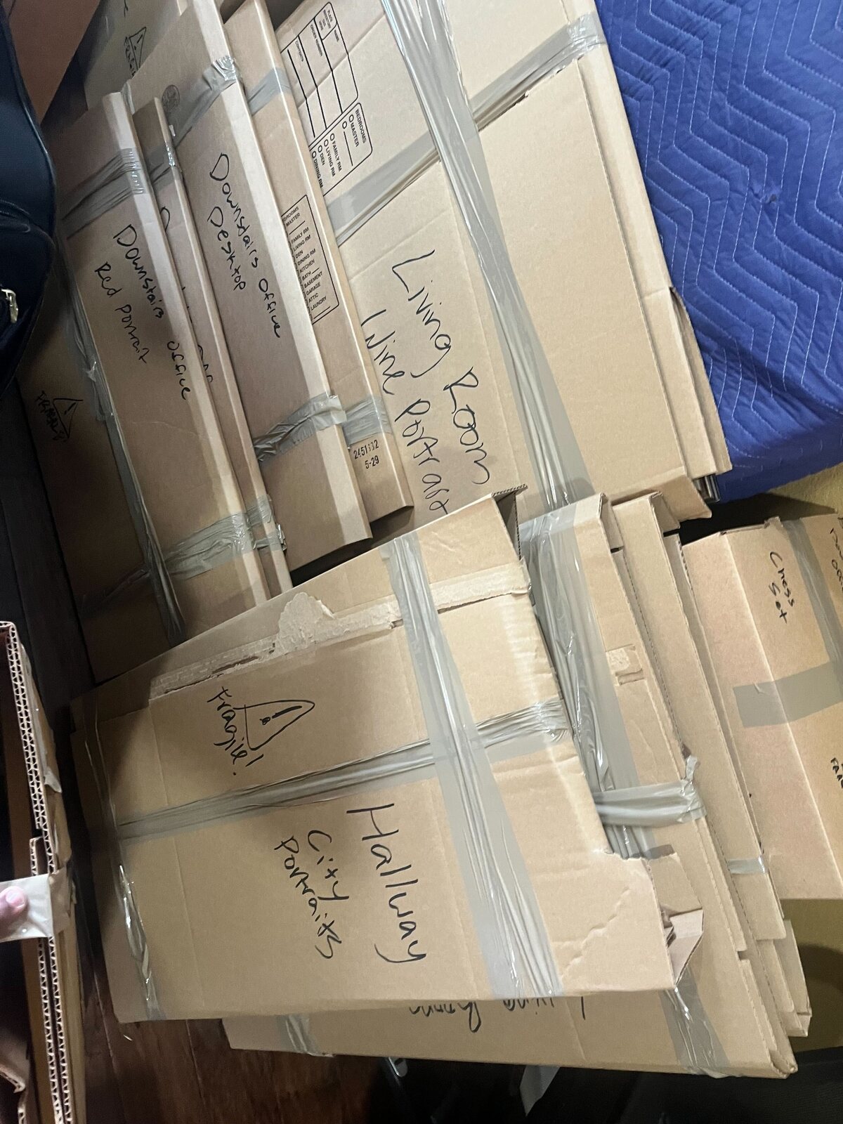 Framed artwork individually protected with cardboard and labeled by destination room